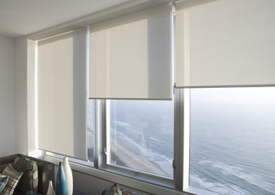 Beach view from window with roller blinds.