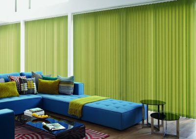 A hotel room with green vertical blinds.