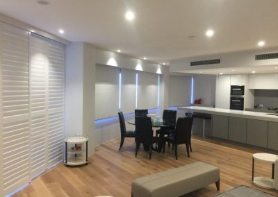 Living room area with interior roller blinds and interior shutters.